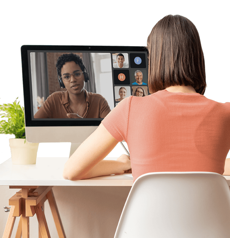 Mulher sentada em uma cadeira em frente a mesa com computador participando de uma videochamada